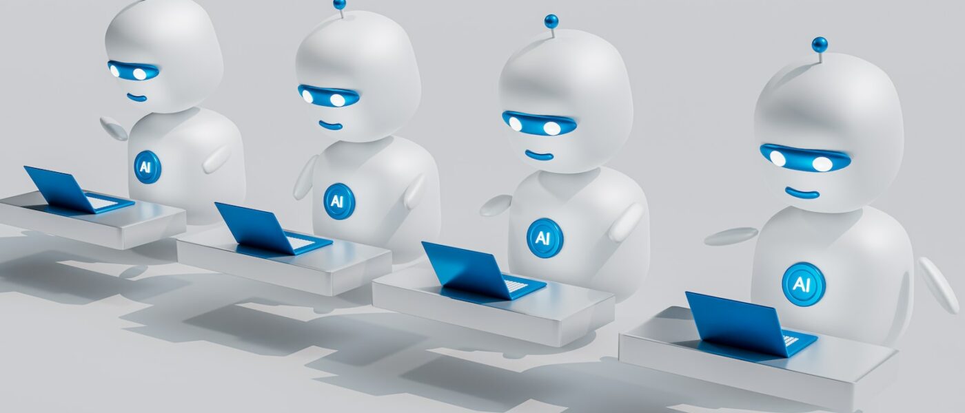 a group of white robots sitting on top of laptops