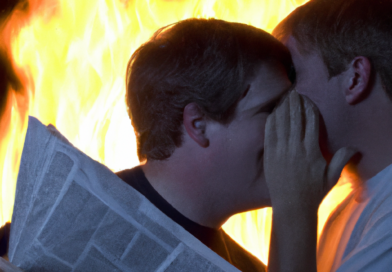 One person whispering in the ear of a newspaper reader, distracting him while the world burns