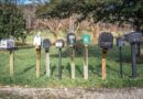 a row of mail boxes sitting on top of a lush green field