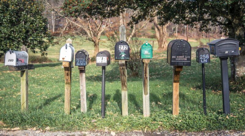 a row of mail boxes sitting on top of a lush green field